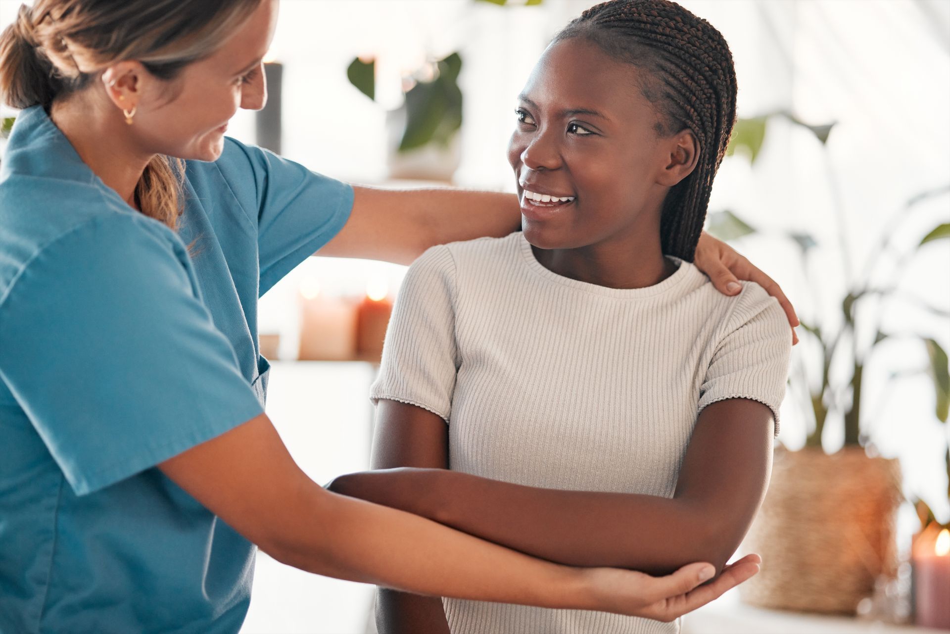 Nurse supporting a patient's arm; both smiling, in a brightly lit room.