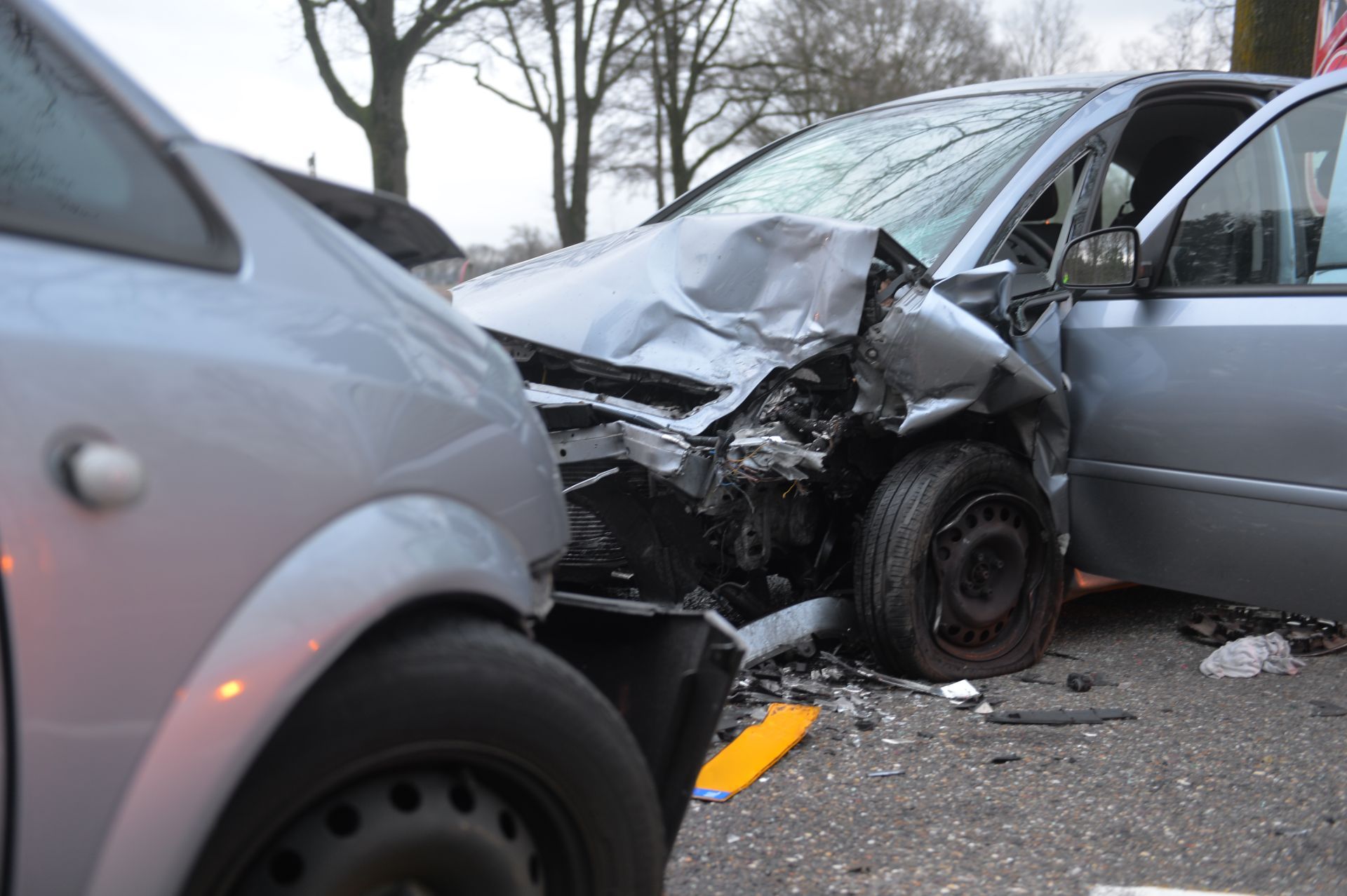 Two damaged silver cars after a collision.
