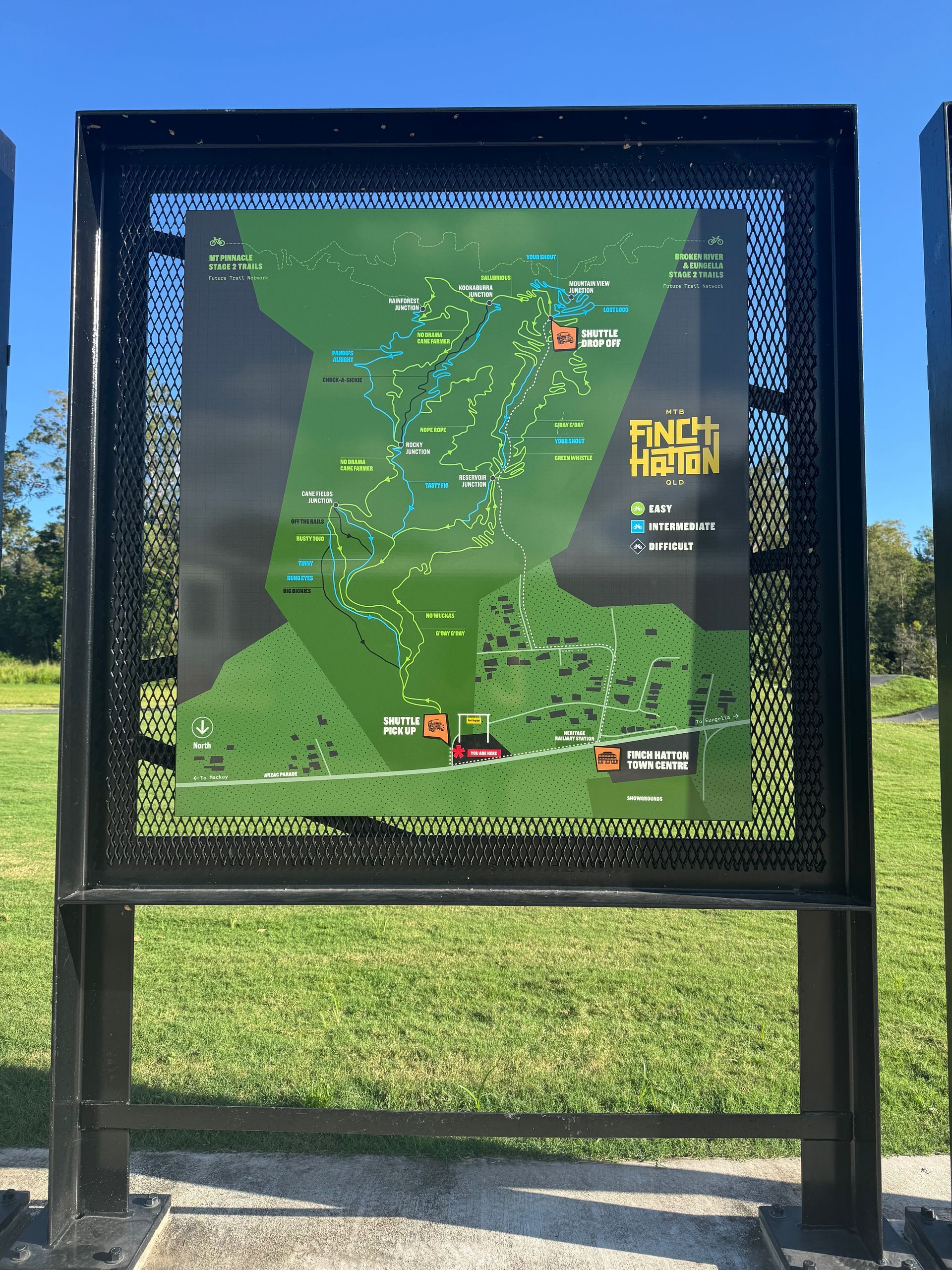 Aerial view of a green, hilly landscape with a cultivated field and mountain bike trails winding through the dense forest.