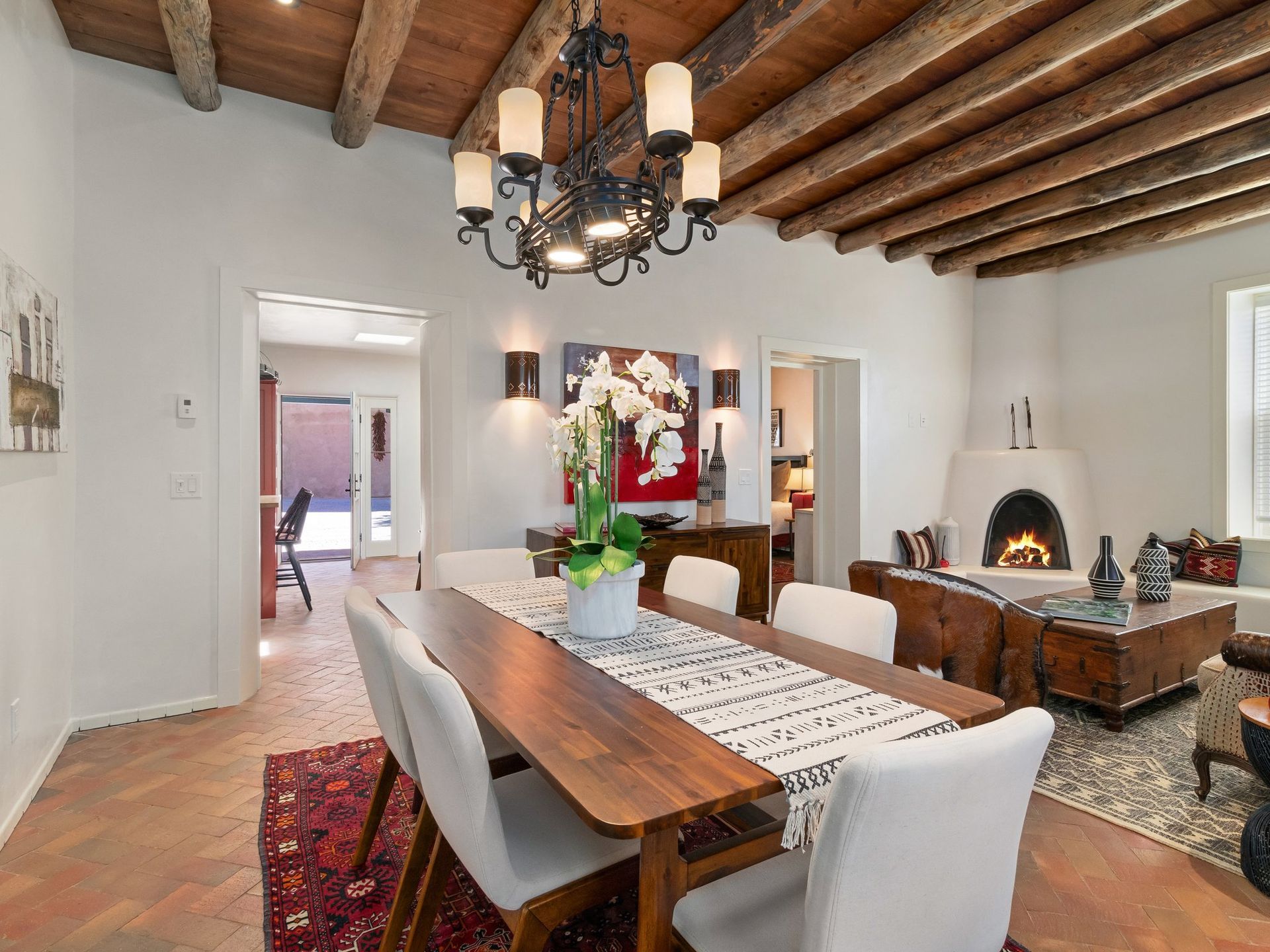 Dining room with wooden table, chandelier, fireplace, and arched doorway.
