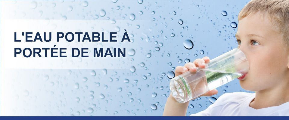 Un jeune garçon boit de l'eau dans un verre.