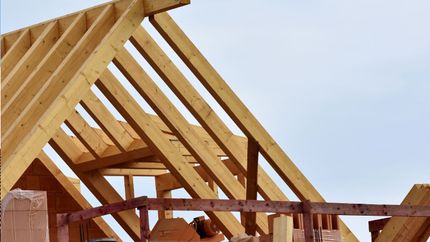 A man is working on the roof of a house under construction