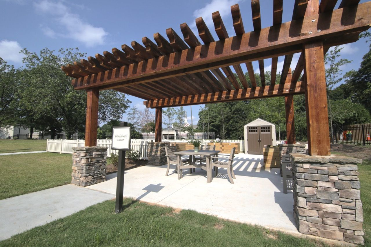 Outdoor community area with a wooden pergola, stone pillars, and patio seating.