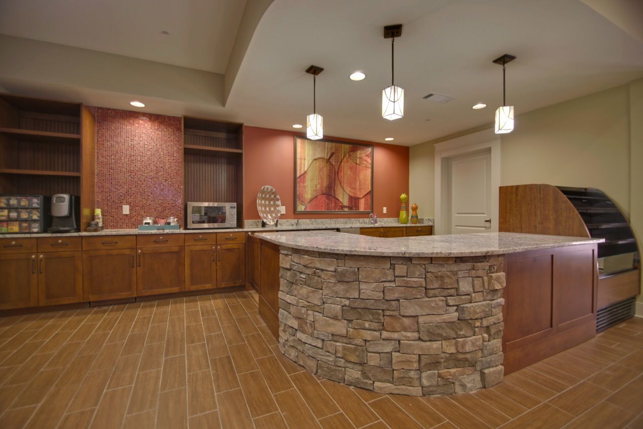 Interior of a communal clubhouse kitchen with a curved stone island.