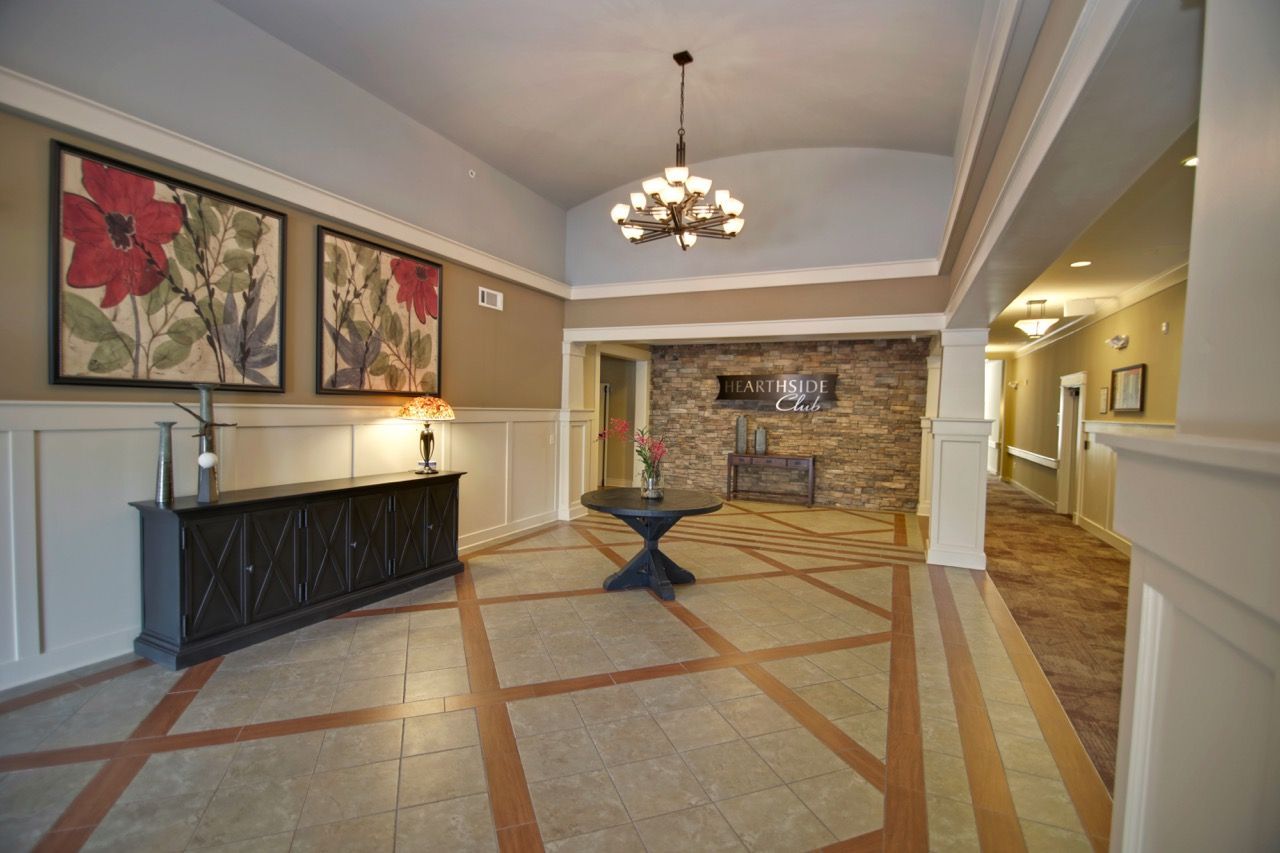 Apartment community lobby with reception desk, round table, chandelier, and brick accent wall.