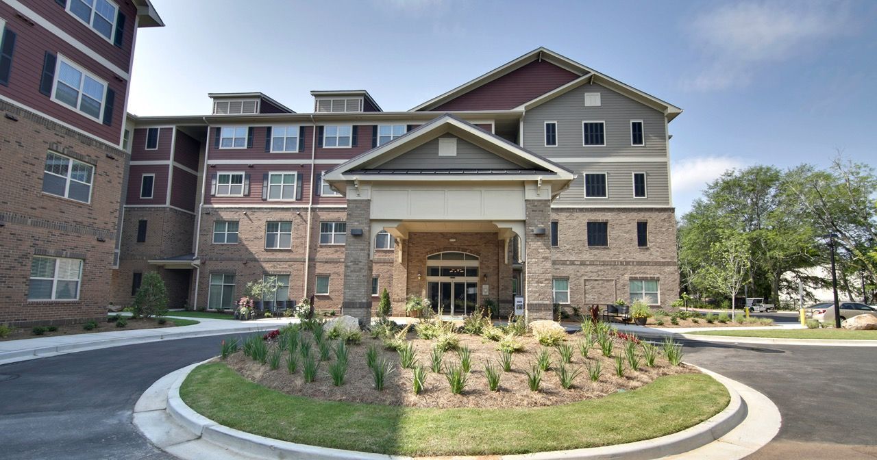 Exterior view of a multi-story apartment building with a circular driveway and landscaped entry.