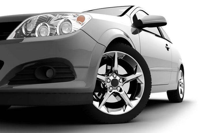 Vista frontale di una coupé sportiva argento con cerchi cromati su sfondo bianco.