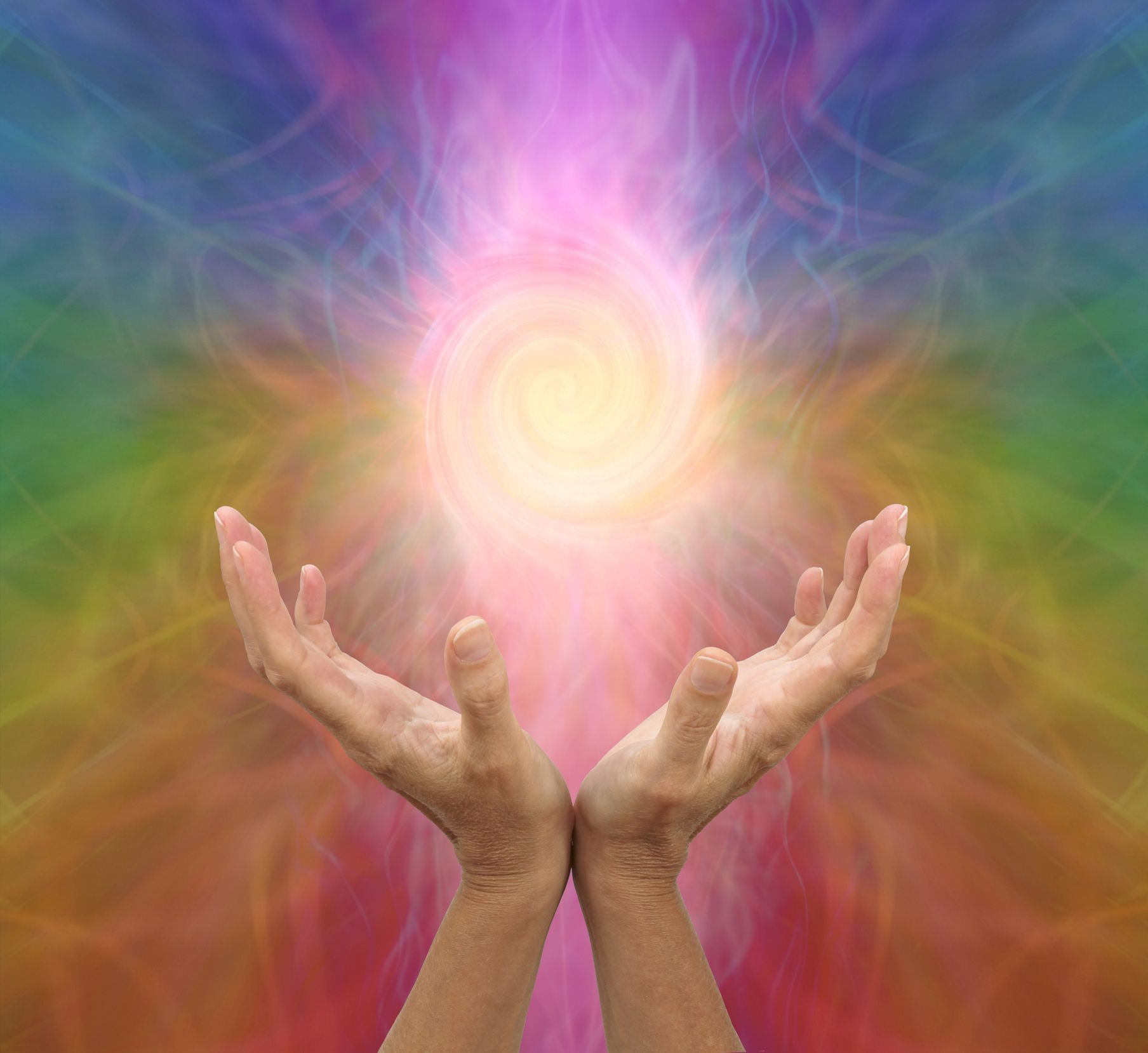 A person is holding a rainbow colored light in their hands.