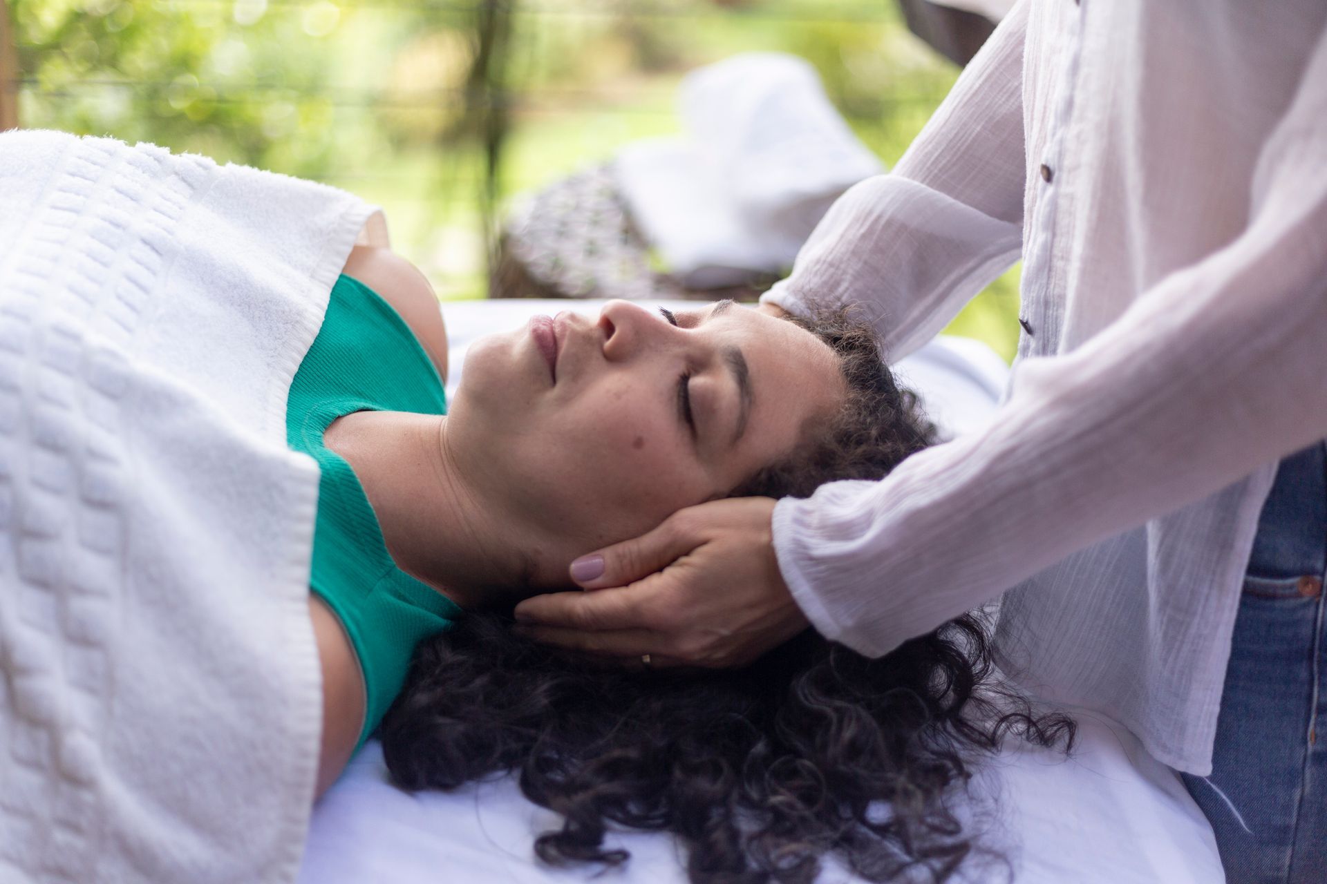 A therapist placing hands on a Latina woman in a reiki session] 