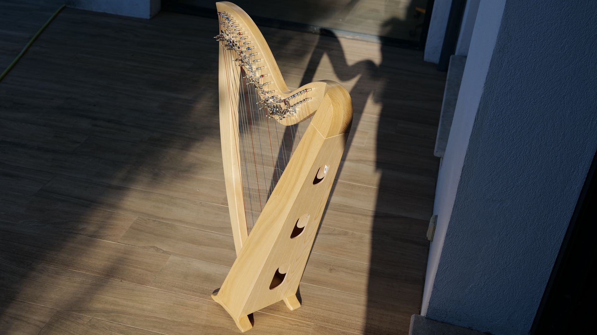 A harp is sitting on a wooden floor next to a wall.