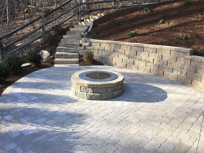 A fire pit is sitting on a patio next to stairs.