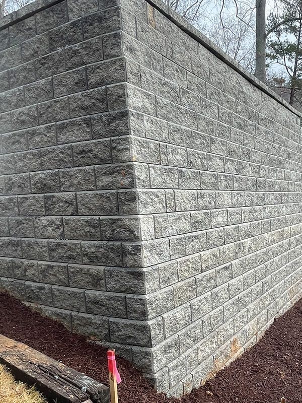 A large brick wall is sitting on top of a pile of mulch.