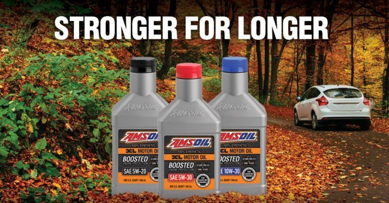 Three motor oil bottles in front of fall foliage and a car on a road. 