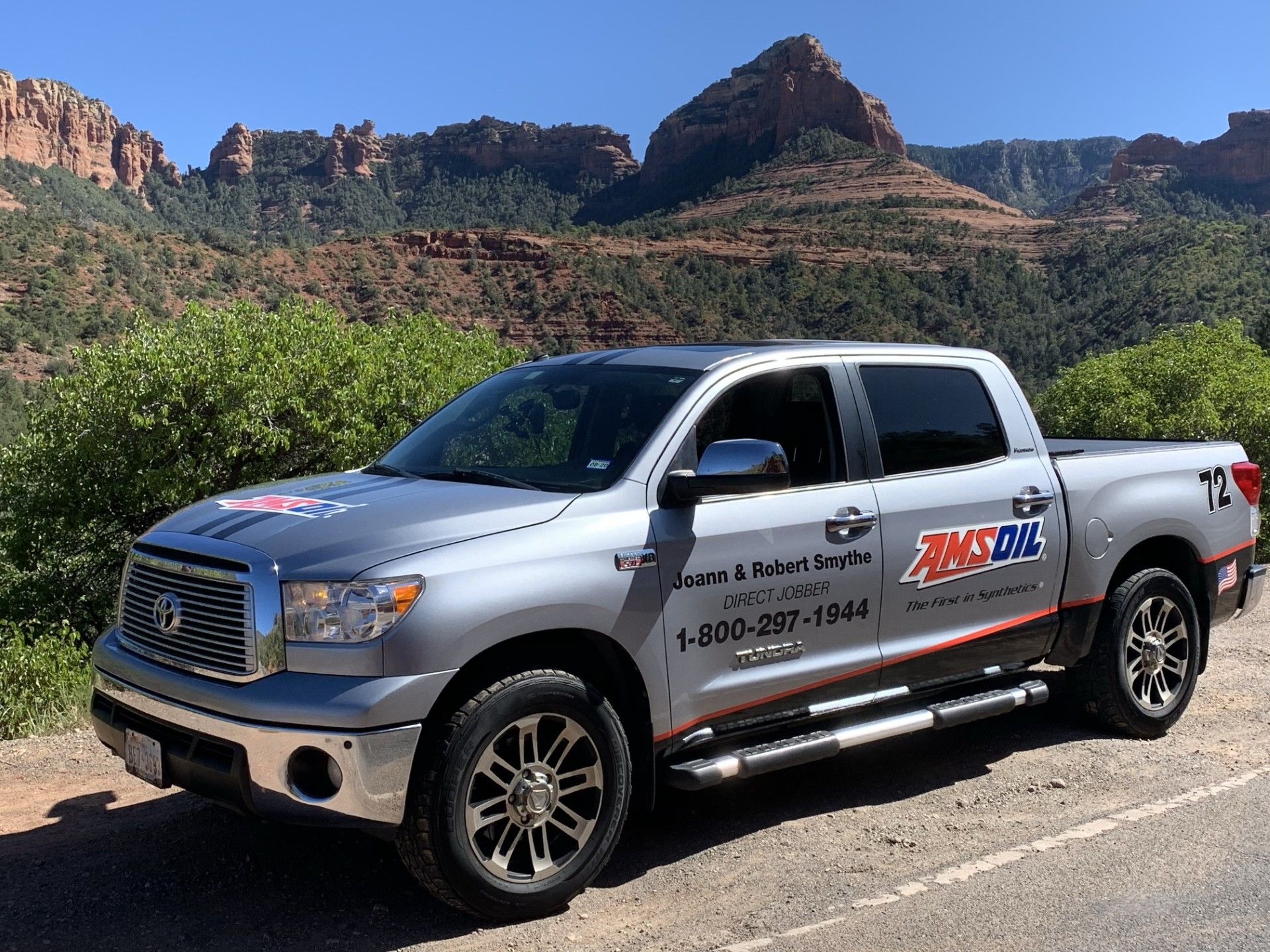 Silver pickup truck with AMSOIL branding parked near red rock mountains in Arizona.