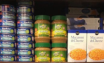 Tuna fish, Peanut butter, and macaroni and cheese on a pantry shelf.