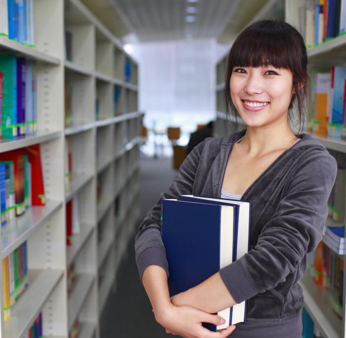 Woman with books in her arms at a library.