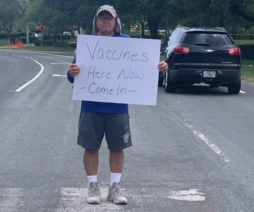 Dan holding up vaccine here now sign.