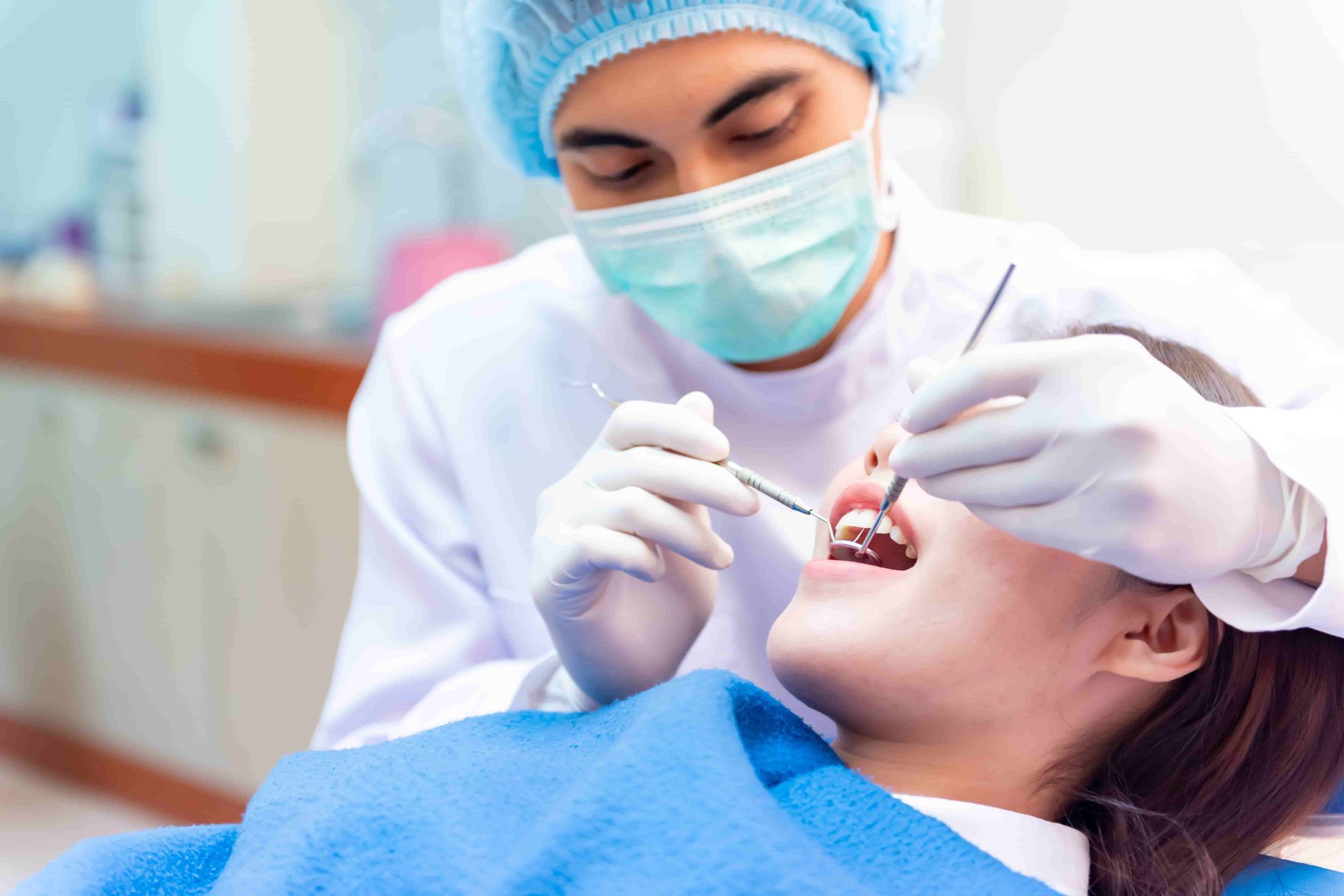 A Dentist is Examining a Woman's Teeth — Central Coast Denture Clinic Erina In Erina, NSW
