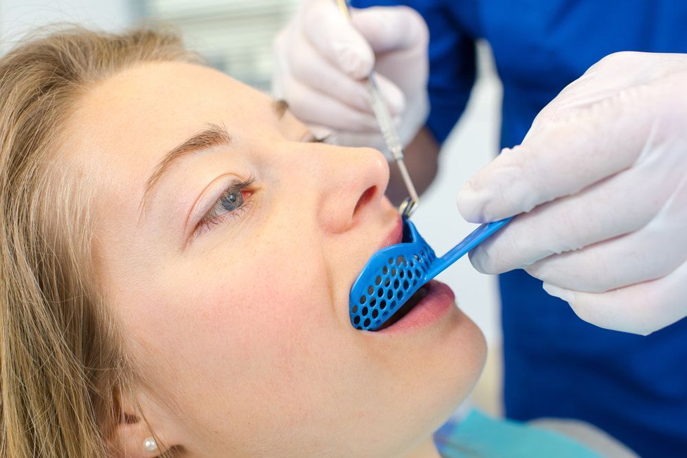 A Dentist Holds a Dental Impression Tray — Central Coast Denture Clinic Erina In The Entrance, NSW