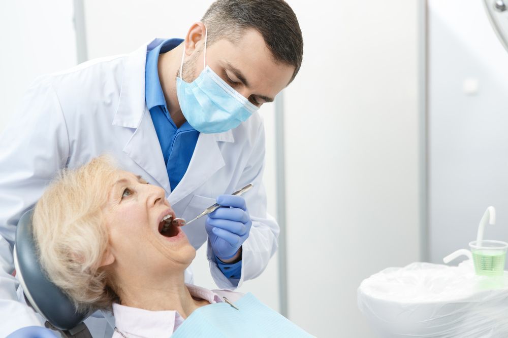 A Dentist Examines an Elderly Woman's Open Mouth — Central Coast Denture Clinic Erina In Kincumber, NSW