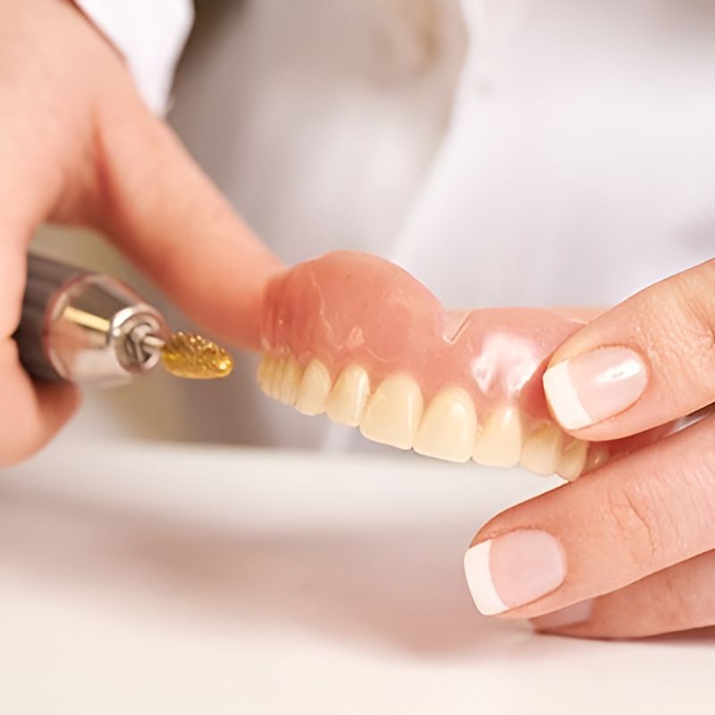 A Person is Polishing a Denture — Central Coast Denture Clinic Erina In Erina, NSW