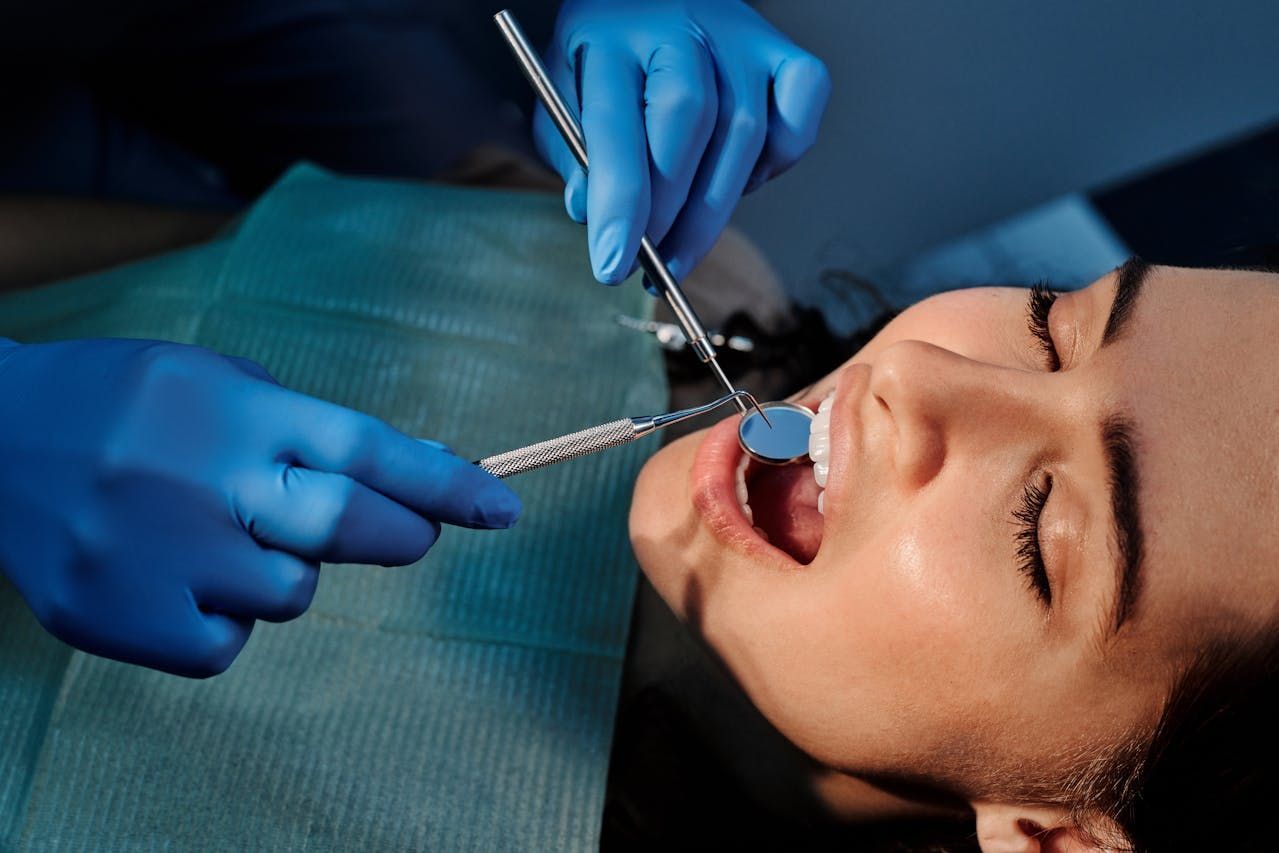 Dentist examining patient's teeth with tools in a dental office.  — Central Coast Denture Clinic Erina In Erina, NSW