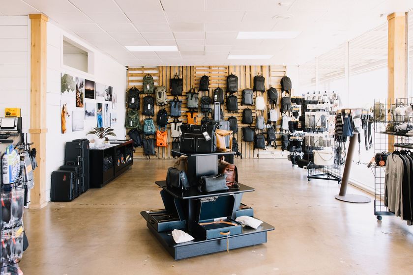 Interior of a retail store with backpacks and bags displayed on walls and shelving.