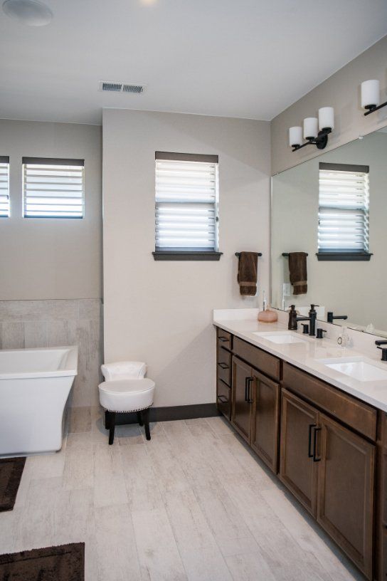 A bathroom with two sinks , a toilet and a bathtub and cellular shades