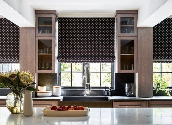 A kitchen with a sink and a bowl of fruit on the counter black roman shades in the kitchen