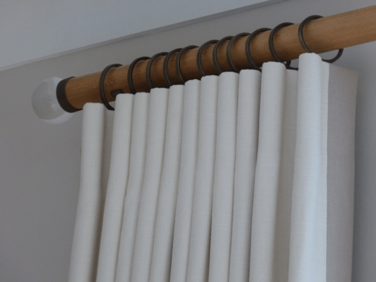 Color White Cartridge Pleat Blinds hanging on wood curtain rod