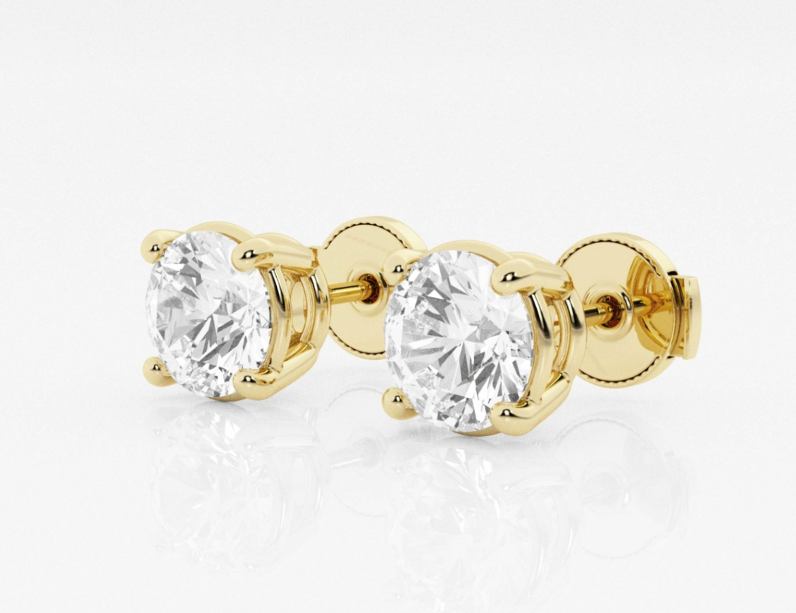 A pair of yellow gold stud earrings with diamonds on a white surface.