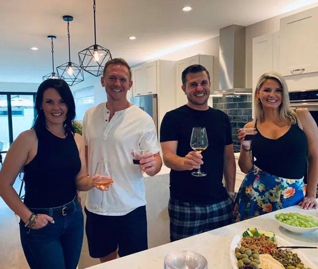 A group of people standing in a kitchen holding wine glasses