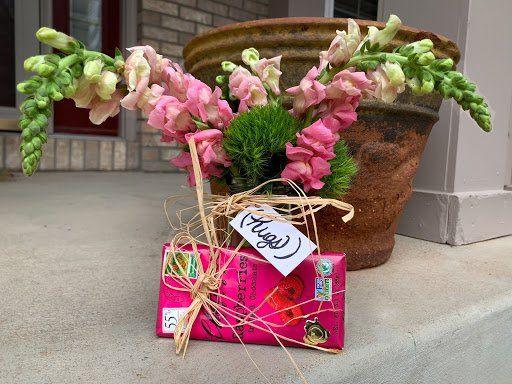 Pink snap dragons with a pink gift wrapped present on a porch