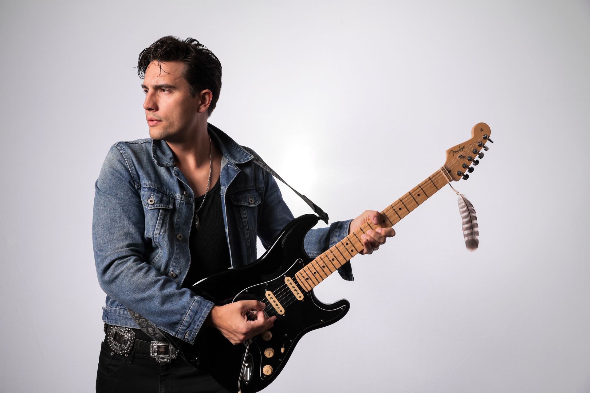 A man in a denim jacket is playing an electric guitar.