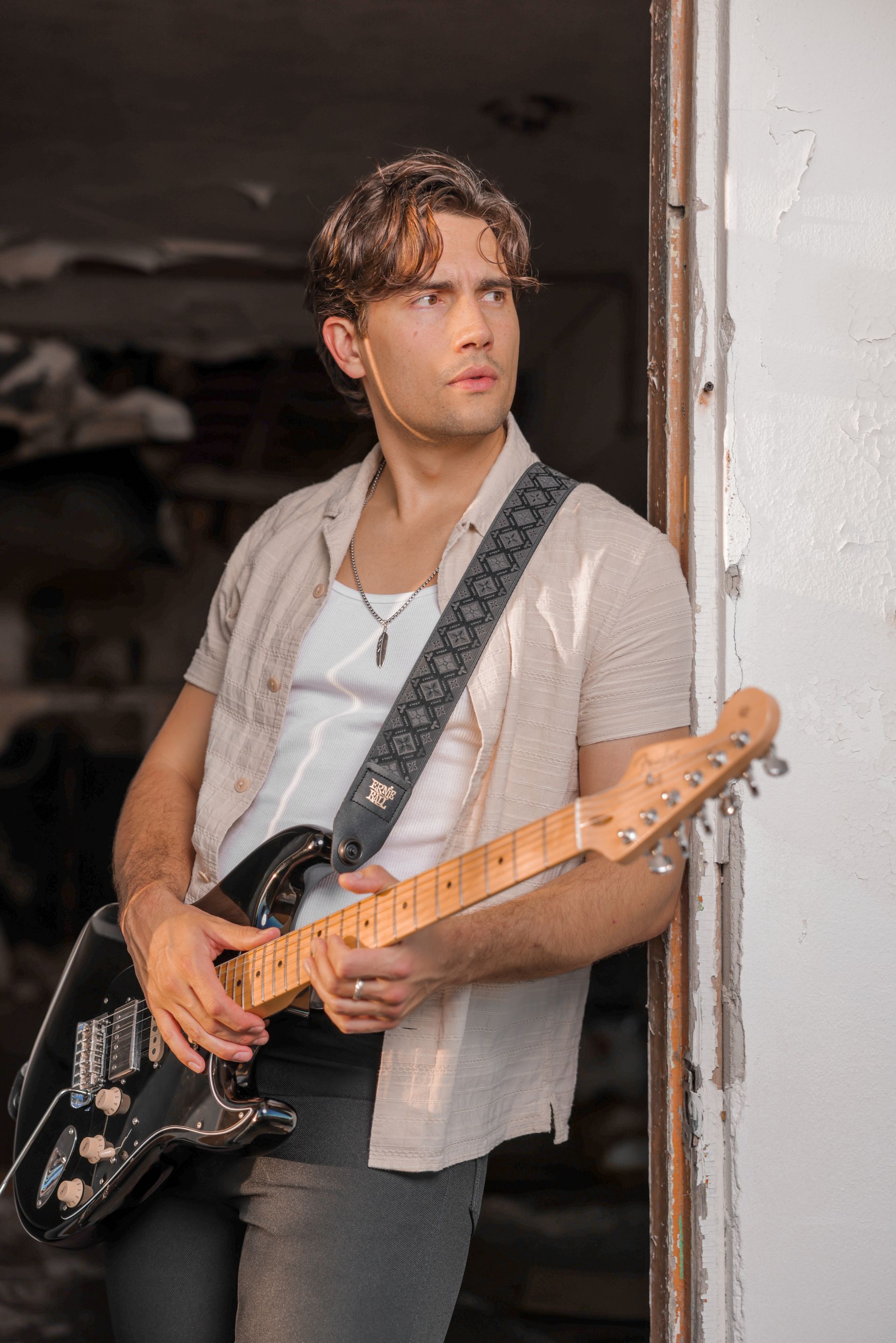 A man is standing in a doorway holding a guitar.