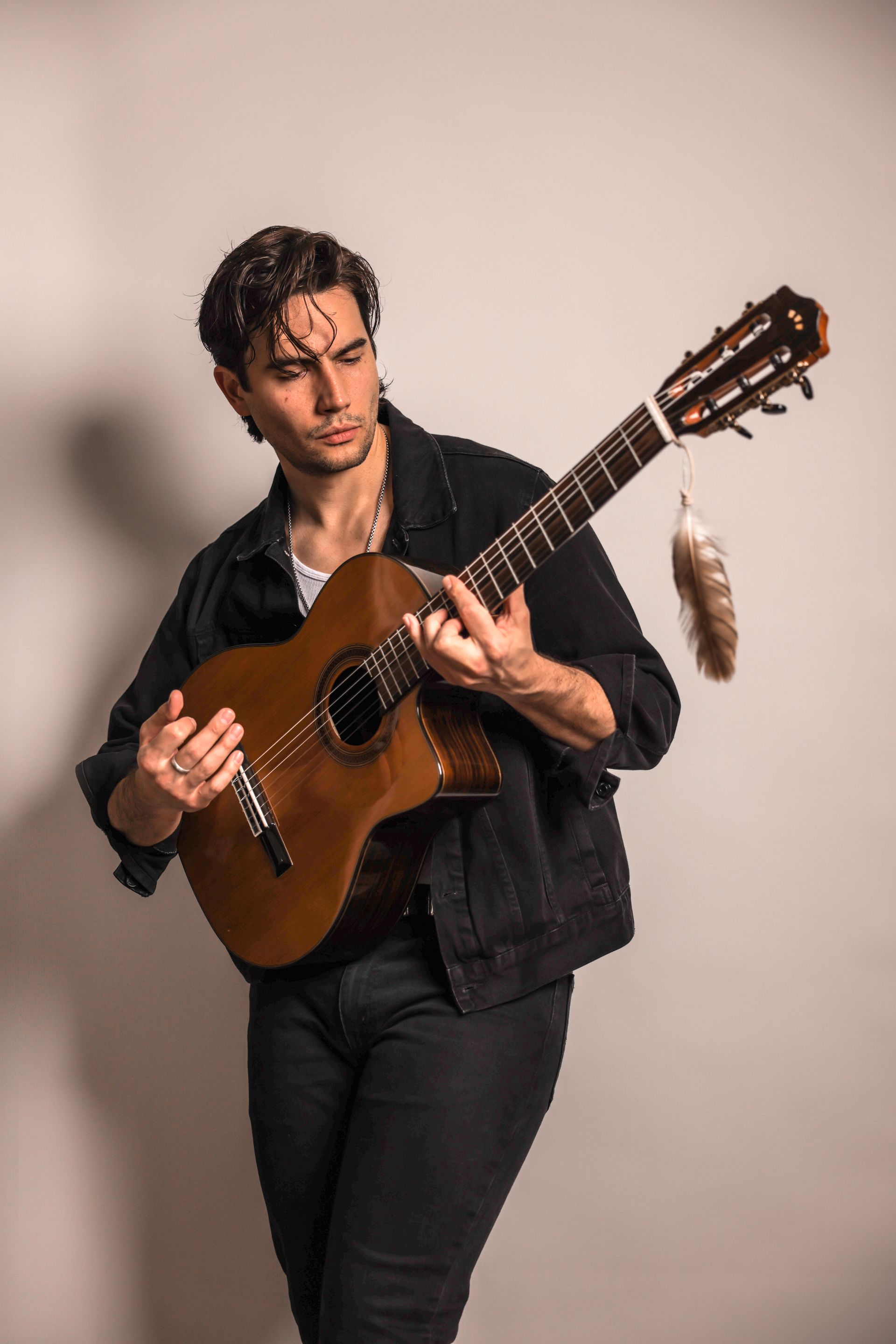 A man is playing a guitar with a feather in his hand.