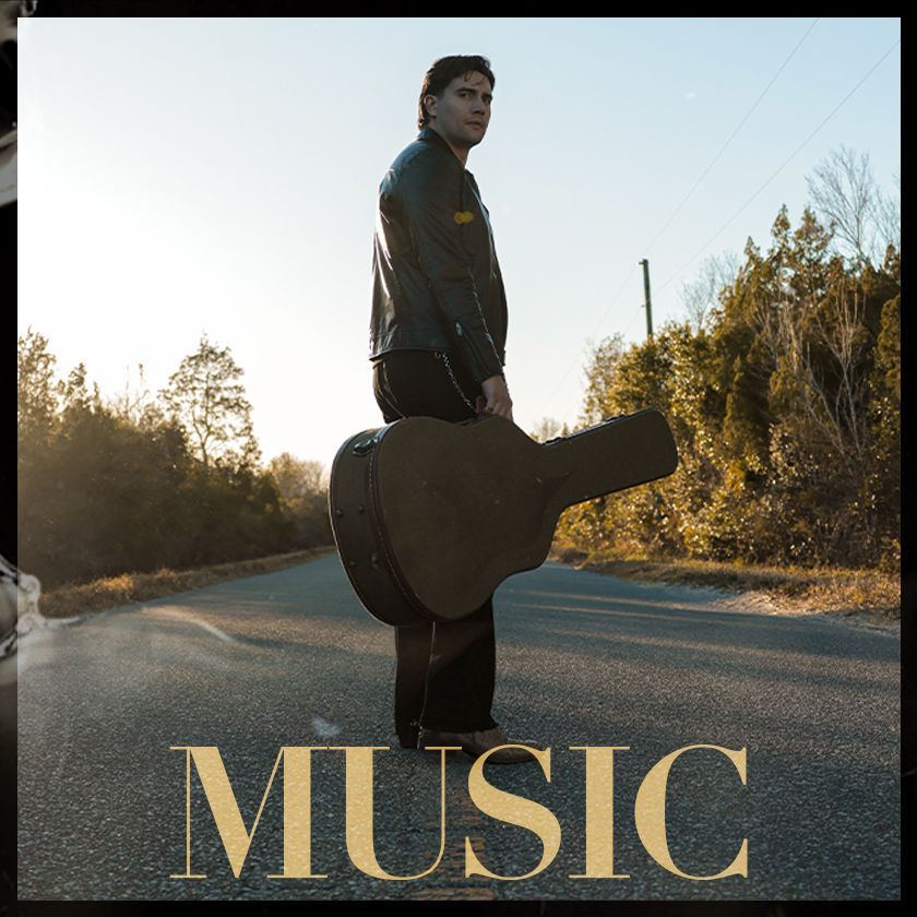 A man standing in a doorway holding a guitar with the word music above him
