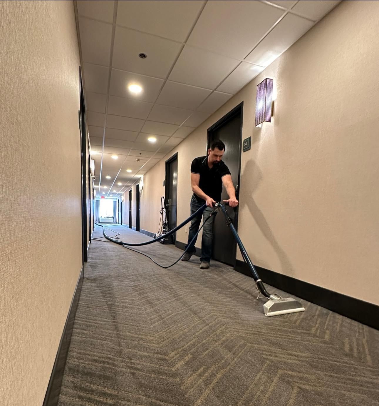 A man is using a vacuum cleaner to clean a hallway