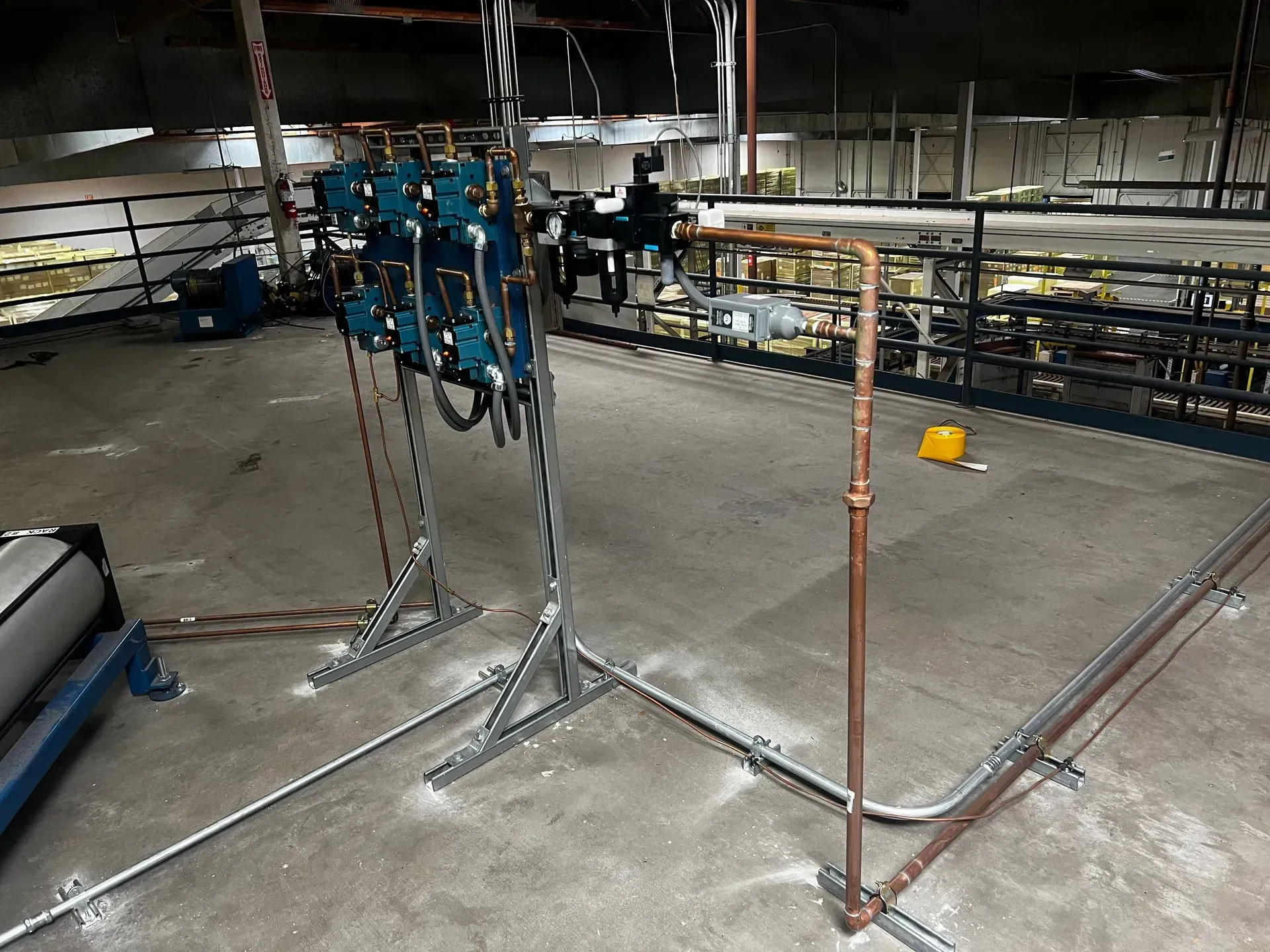 Industrial interior with metal pipes and machinery. Gray concrete floor, dark walls.