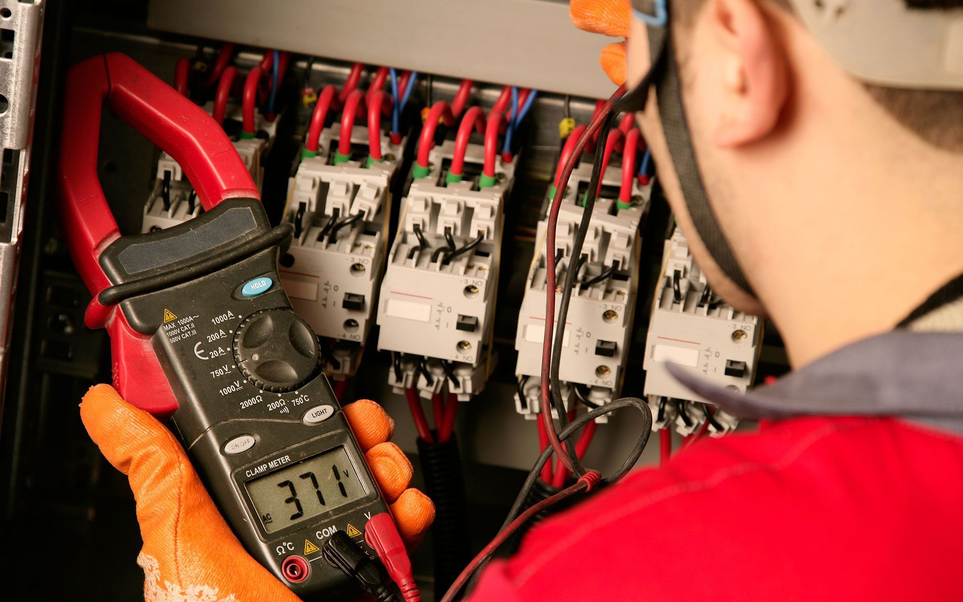 A man is using a clamp meter to test a circuit board.
