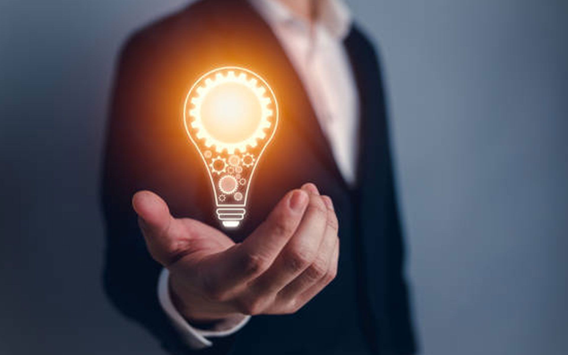 A man in a suit is holding a light bulb in his hands.