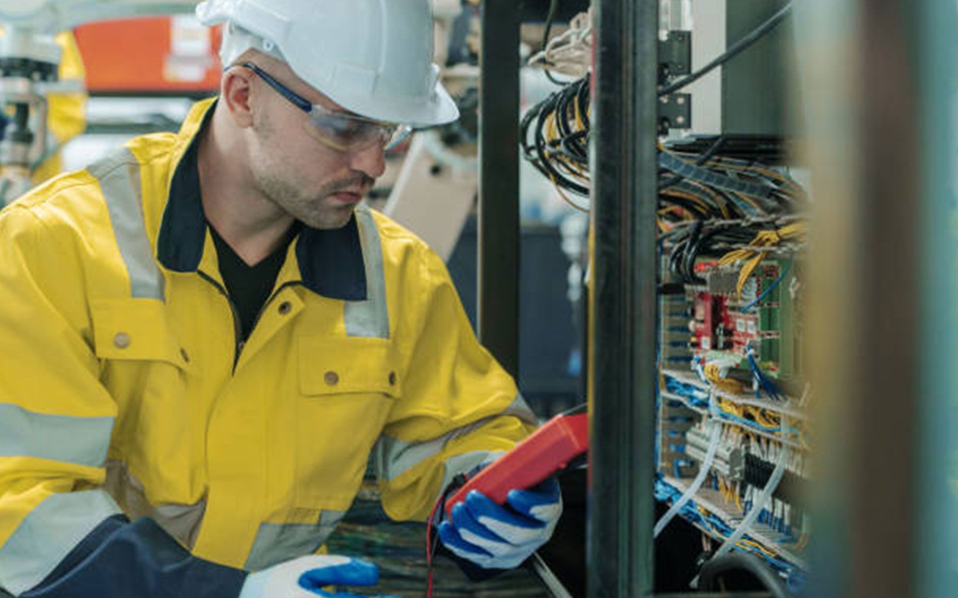 An electrician is working on a machine in a factory.
