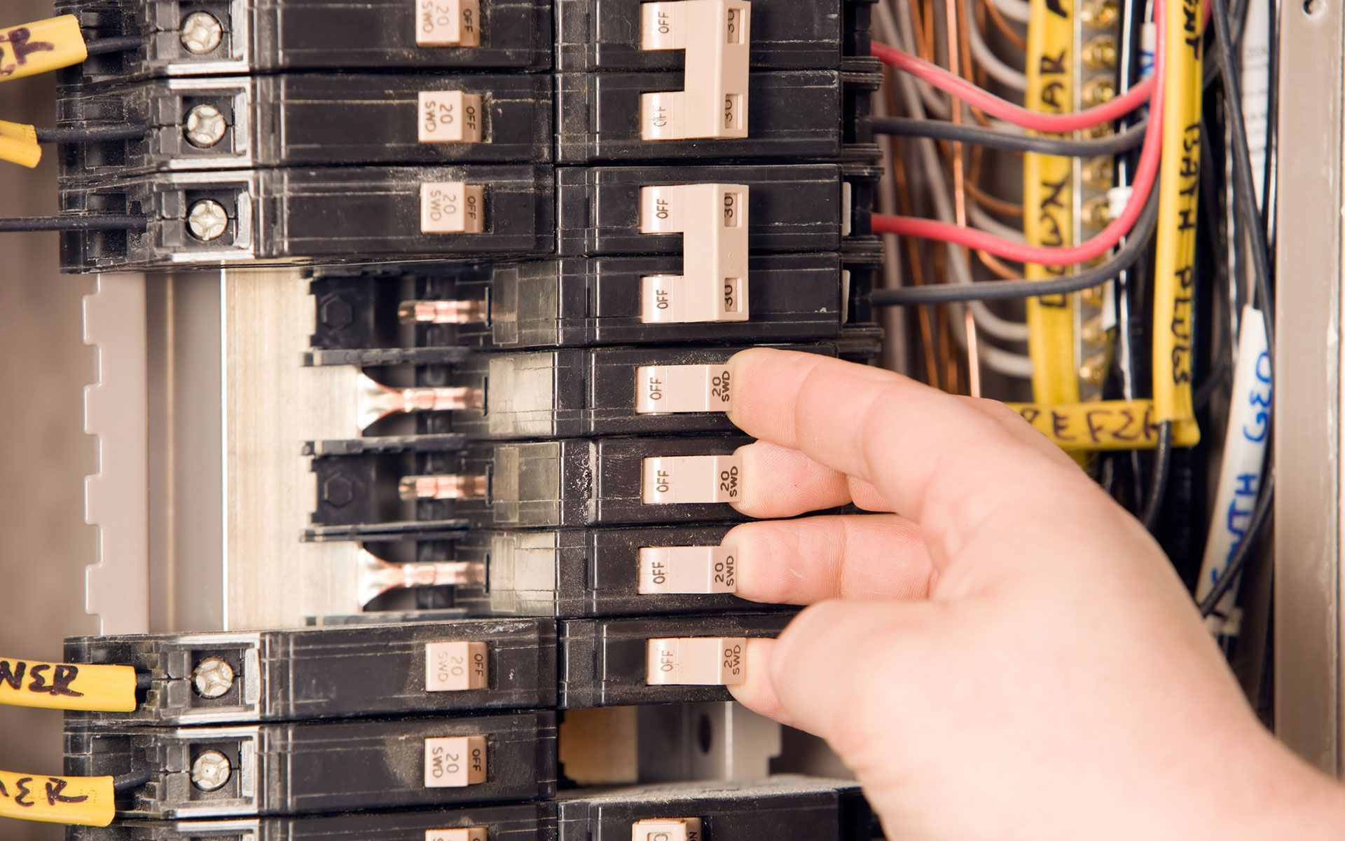 A person 's hand is reaching into an electrical box.