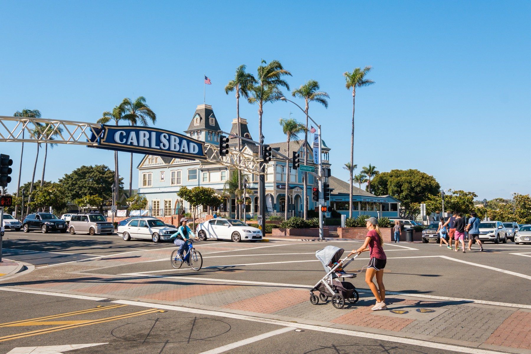 A woman is pushing a stroller through a busy intersection.