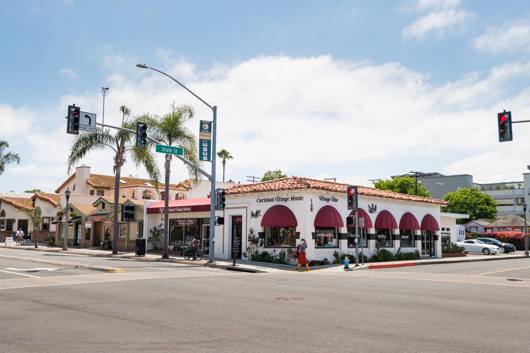 A white building with red awnings is on the corner of a street.