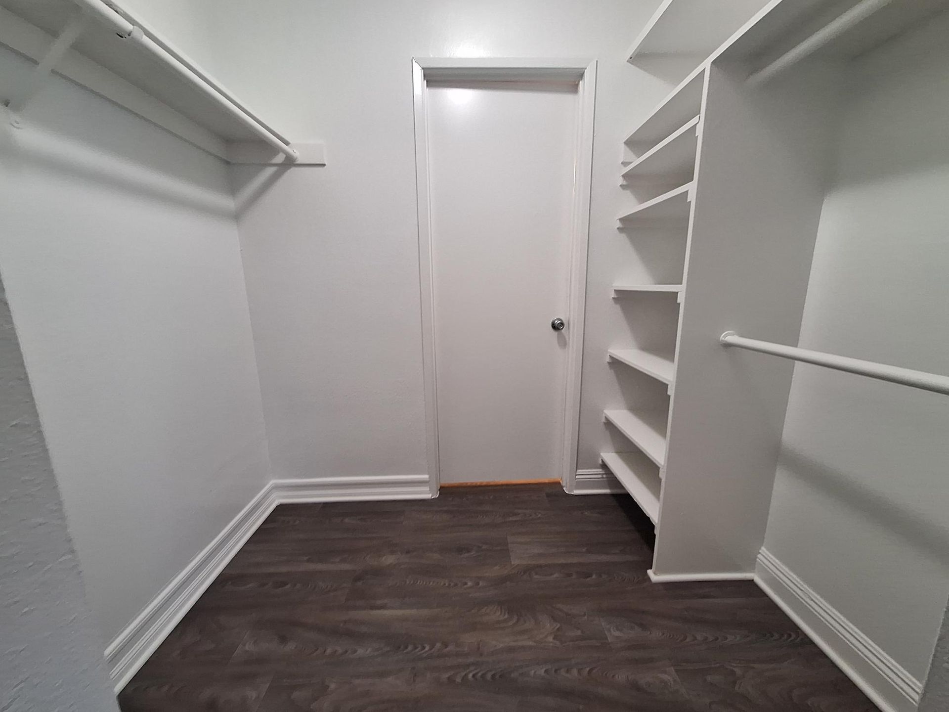 A walk in closet with lots of shelves and a door.