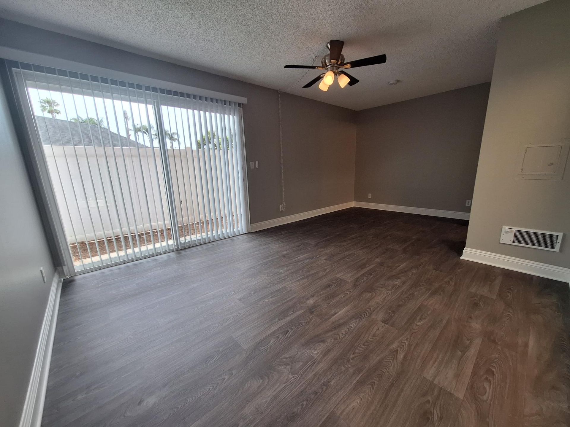 A living room with a ceiling fan and sliding glass doors.