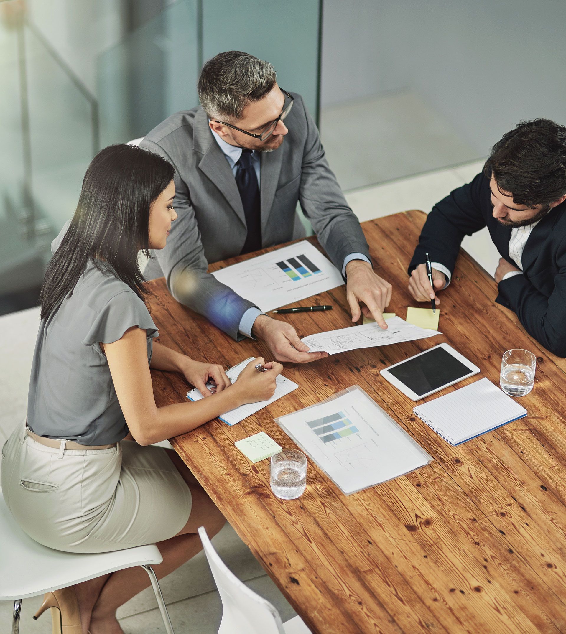 A group of people are sitting around a wooden table having a meeting.