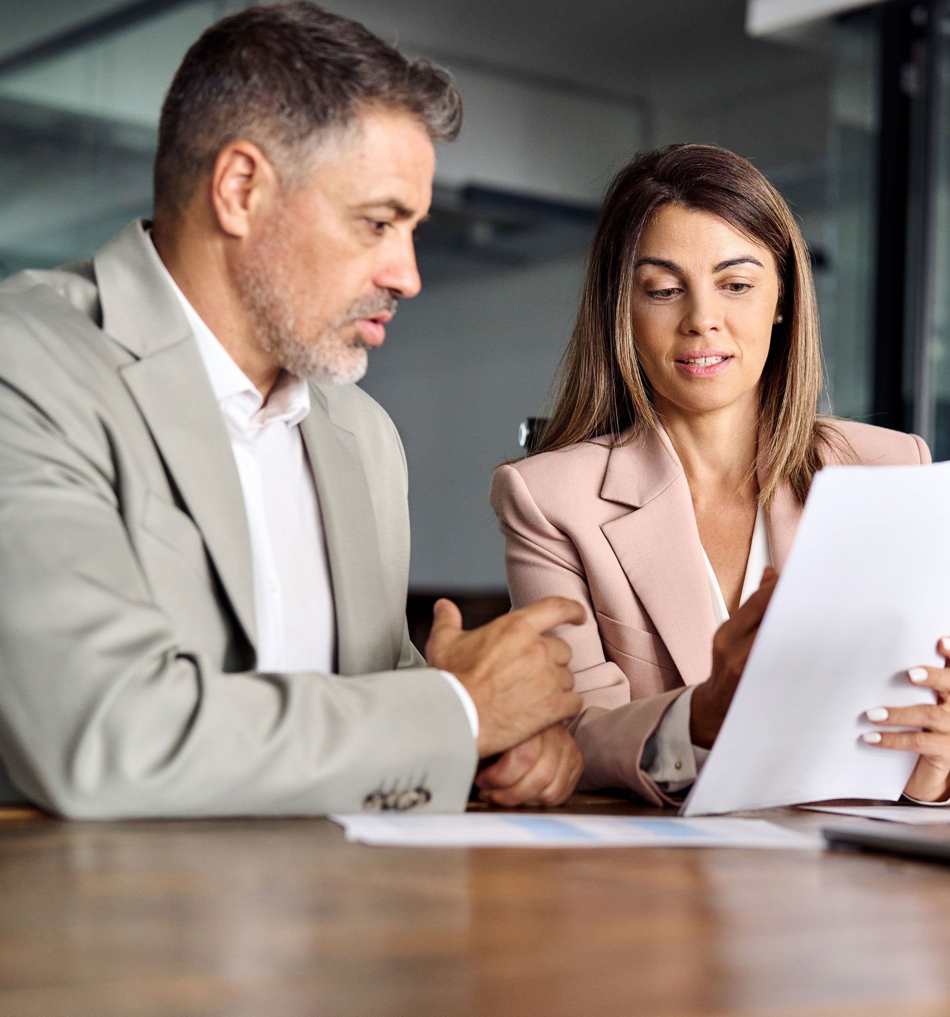 A man and a woman are sitting at a table looking at a piece of paper.