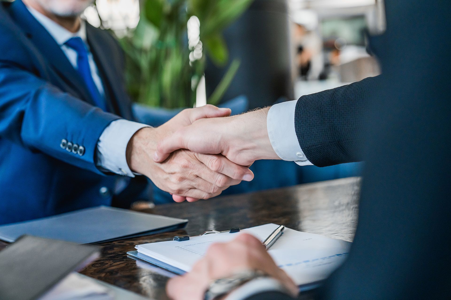 Two businessmen are shaking hands while sitting at a table.